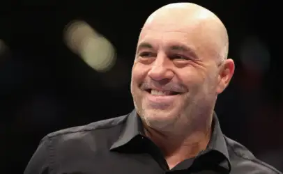 Smiling bald man in a black collared shirt, looking off to the side.