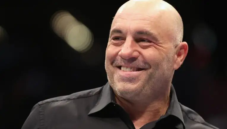 Smiling bald man in a black collared shirt, looking off to the side.