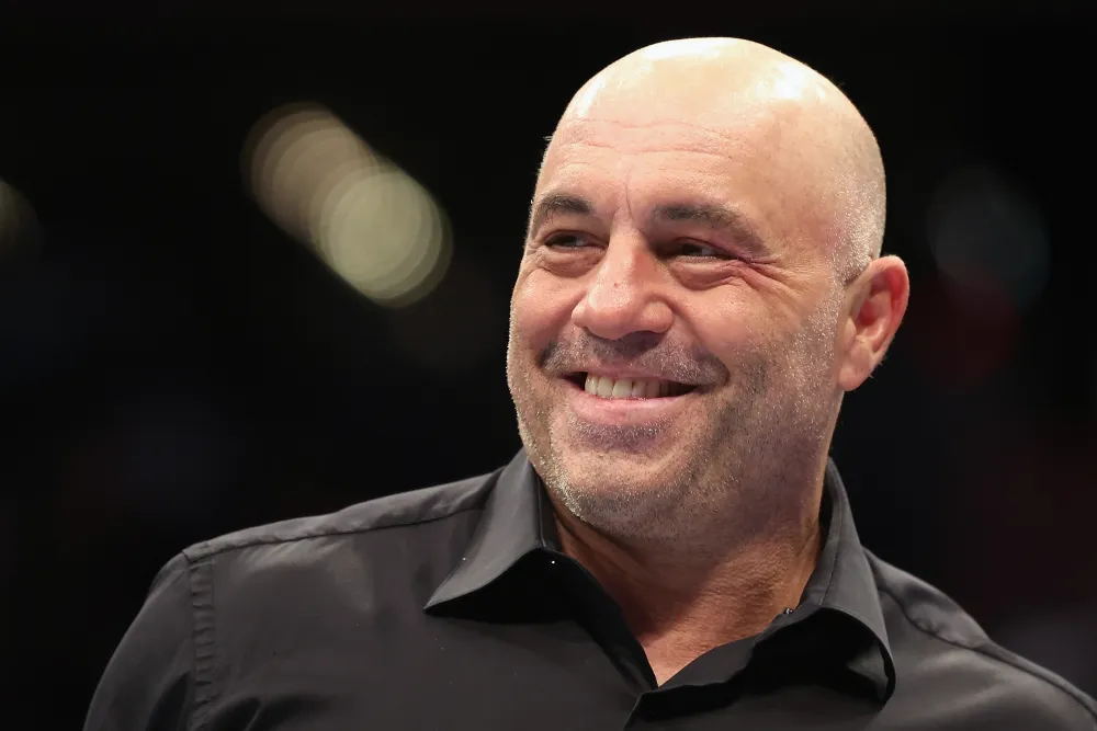 Smiling bald man in a black collared shirt, looking off to the side.