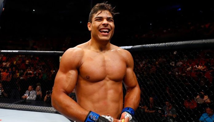 Smiling muscular male MMA fighter in a cage, wearing blue gloves, celebrating after a fight.
