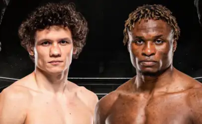 Two shirtless male boxers pose inside a boxing ring, facing the camera with serious expressions.